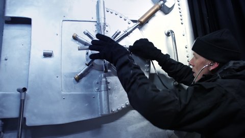 A bank robber cracking a safe. The safecracker uses a stethoscope to crack the vault security lock