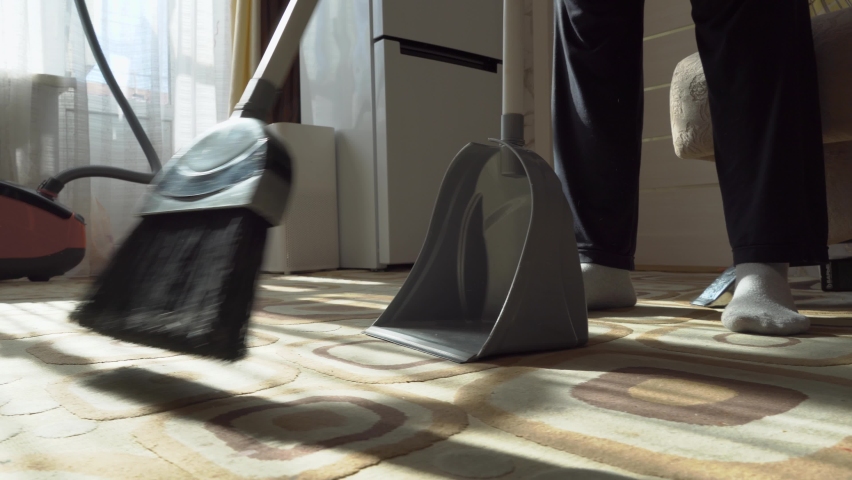 Cleaning.Clean up the garbage from the floor with a broom for cleanliness.Sweep away dust and dirt with a brush into a dustpan.Sweeping the carpet with a broom at home.Indoor cleaning tools. | Shutterstock HD Video #1088770251