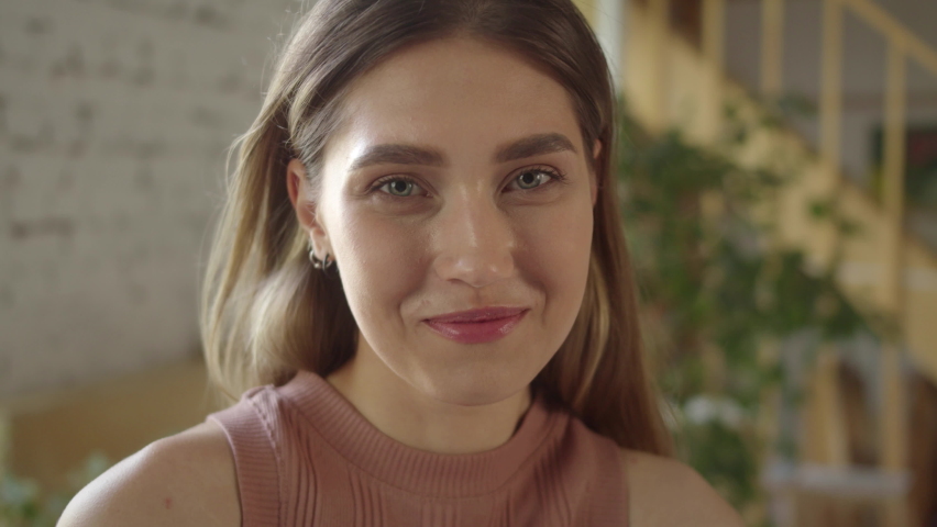 A young attractive lady with long hair and blue eyes is posing and looking at the camera