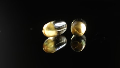 Omega 3 Gold oil capsules on black background, rotation. Close-up of rotating golden pills.Vitamins supplements pills omega 3. Cod liver oil medicines. Fish oil capsules.Omega 3 Fish oil vitamin gel