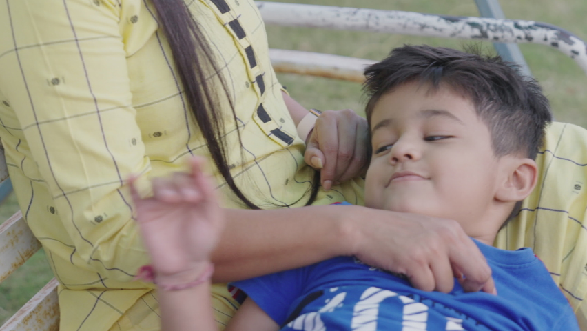 
Indian beautiful Mother with her cute son laying his head on mother’s lap sitting on swing in green garden playing together or having fun.Mother’s care for his child. Mother's Day concept.Slow motion Royalty-Free Stock Footage #1088777521
