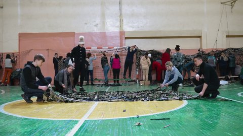 Ukraine, Chernivtsi - March 4, 2022: Many people voluntarily weave camouflage nets in the gym. Nets for soldiers who defend the country from enemy aggression. War. Protection during hostilities.