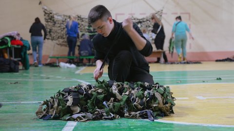 Ukraine, Chernivtsi - March 4, 2022: People voluntarily weave camouflage nets for the military to protect the country from enemy aggression. War. Protection during hostilities.