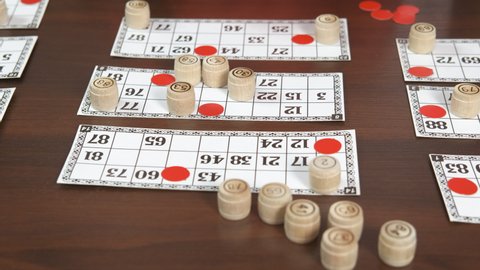 Board with bingo game. Two girls play with board lotto with barrels with numbers on the table.