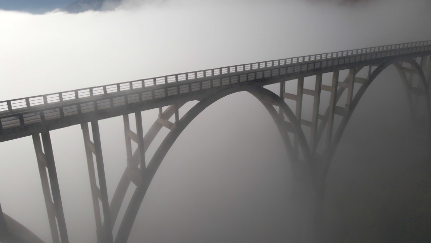 Aerial video of the magnificent Djurdjevica Bridge over the Tara river canyon in the northern part of Montenegro. Beautiful morning fog moves through the arches of the bridge. Shot in the fall season