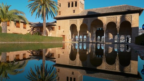 Granada Alhambra, Unesco Site in Spain. A large central pond faces the arcade which stands behind Tower of Ladies reflecting in water.