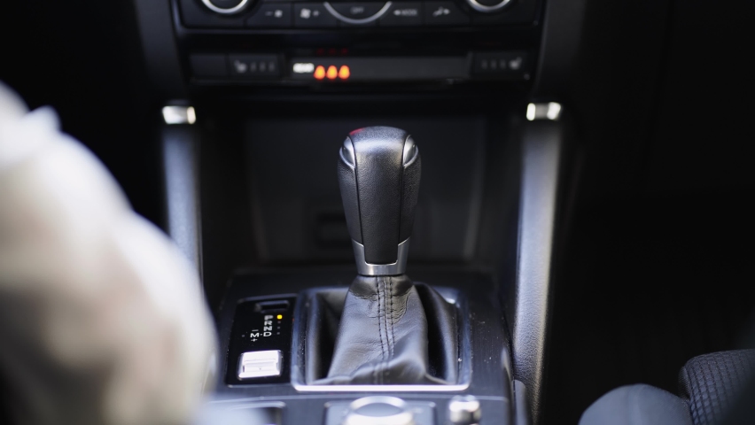 Unrecognizable woman driver shifting the gear stick and driving a car, hold transmission.