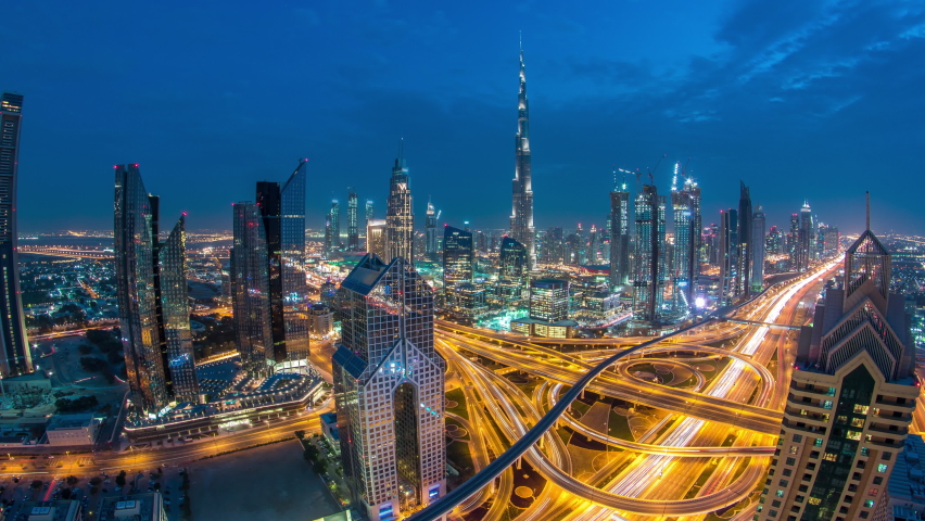 Modern skyscrapers and busy evening highways day to night transition timelapse in luxury downtown of Dubai city. Top aerial view from tower rooftop. Road junction traffic. Fisheye lens. Dubai, United Royalty-Free Stock Footage #1088787217