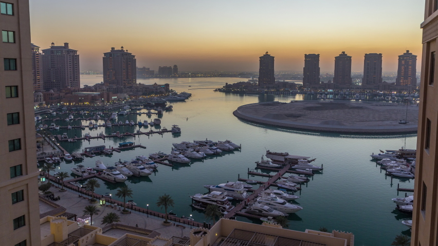 Evening at the Pearl-Qatar day to night timelapse from top. Aerial view of the Marina and residential buildings in Porto Arabia in Doha, Qatar, Middle East. It is an artificial island in Qatar.