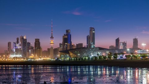 Seaside skyline of Kuwait city from night to day transition timelapse. Modern illuminated towers and skyscrapers reflected in water.