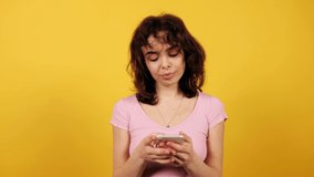 Beautiful girl texting. Attractive young woman on yellow background.