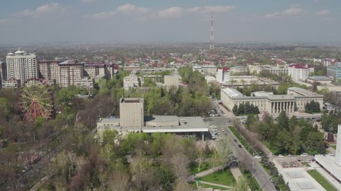 Aerial cinematic footage of Bishkek city. Aerial landscape city with building and ferris wheel. Drone filming close-up of Kyrgyzstan capital city. Soviet architecture in the center of Asia.