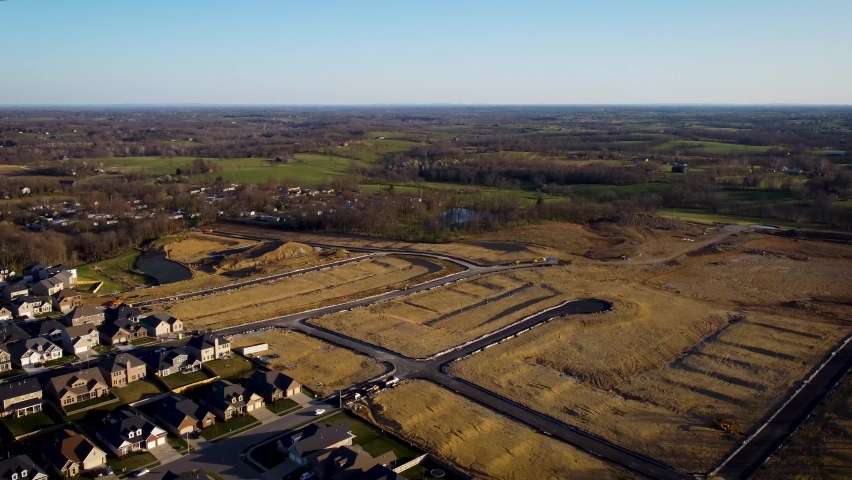 Circling around grounds prepared for building new homes for neighborhood expansion of Lexington, Kentucky. Lots are cleared and local roads are ready for construction process.