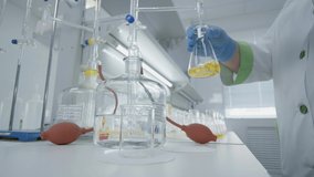 Scientist Chemist Mixing In Laboratory Yellow Liquid. Laboratory Researcher in Blue Gloves  - Powered by Shutterstock - Get 15% off with code: PIKWIZARD15