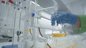 Scientist Chemist Mixing In Laboratory Yellow Liquid. Close up Blue Gloves - Powered by Shutterstock - Get 15% off with code: PIKWIZARD15
