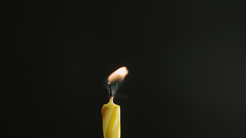 Single big yellow candle flame lights and extinguish, isolated on a black background, Slow motion, central framing Royalty-Free Stock Footage #1088795025