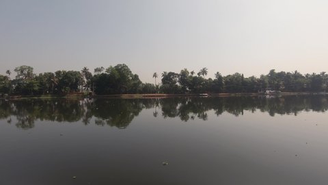 Trees reflecting on river calm waters of Alappuzha in India. Side view