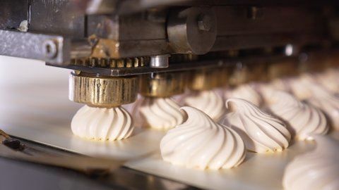 Spinning nozzles of an automatic machine produce marshmallows. Sweet desserts production at confectionary. Close up.