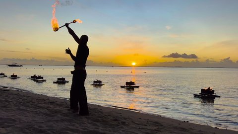Cool fire show artist breathes fire in dark air, performing amazing stunts on the background of the ocean