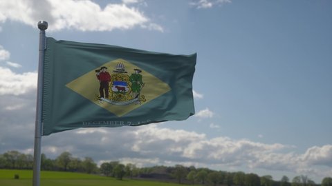 Delaware flag on a flagpole waving in the wind in the sky. State of Delaware in The United States of America