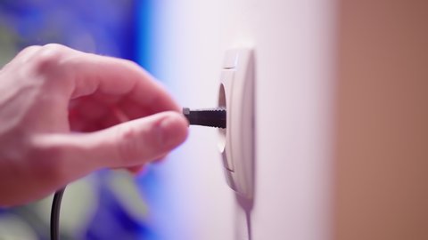 Plug in and plug out of electric outlet thin black cable close-up 4K