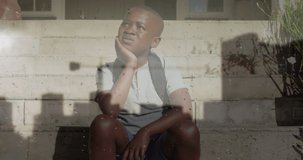 Animation of cityscape over sad african american boy sitting on stairs. childhood, loneliness, emotions and trauma concept digitally generated video.