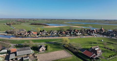 Small historic typical dutch polder farm village in green countryside sunny spring landscape with waterway and canals. Agriculture and grass land.