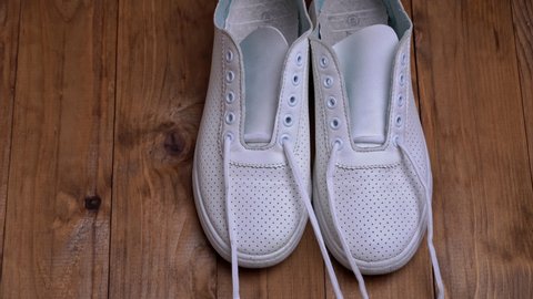Girl's hands are lacing up white sneakers in a fast-paced shot. Tie laces to a bow. Close-ups of women's shoes with stretching laces.