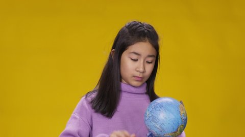 Asian girl spins globe, chooses country and laughs