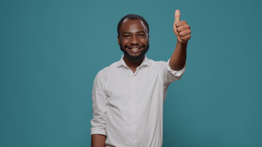 African american man giving thumbs up in front of camera, expressing positivity and satisfaction. Young optimistic person doing approval symbol with hand, giving like to excellent idea.
