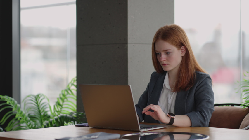 successful woman boss is working with laptop in modern office, pretty lady is typing message in work chat