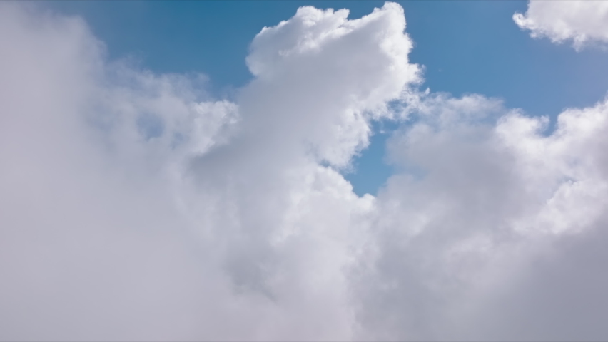 Flying through fluffy white clouds in clear blue sky. Cumulus white cloud cloudscape, summer blue sky time lapse. Nature weather blue sky background. Cloud time lapse nature background 4K aerial