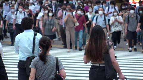 TOKYO, JAPAN - SEP 2020 : Back shot of people and crowd wearing surgical masks at the street. View of commuters with masks to protect from Coronavirus (COVID-19). Slow motion. Medical concept video.