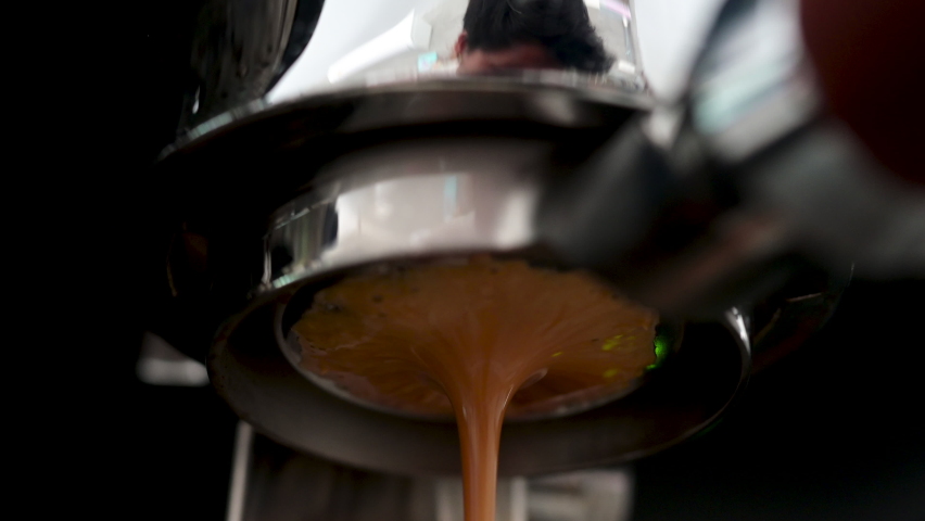 Pouring coffee stream from professional machine in cup. Barista man making espresso shot by bottomless, using filter holder. Flowing fresh ground coffee. Drinking roasted black coffee in the morning | Shutterstock HD Video #1088810077