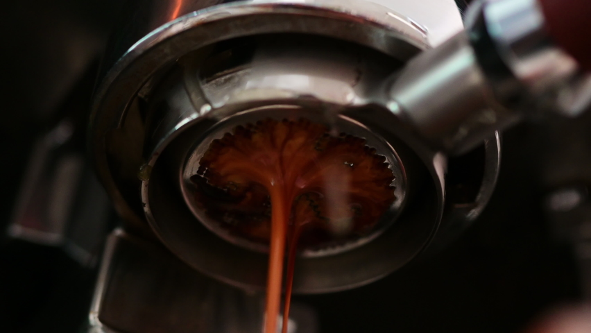 Pouring coffee stream from professional machine in cup. Barista man making espresso shot by bottomless, using filter holder. Flowing fresh ground coffee. Drinking roasted black coffee in the morning | Shutterstock HD Video #1088810079
