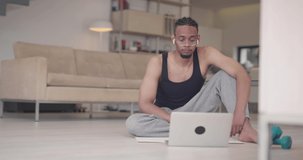 African American fitness trainer using laptop for online training with client during coronavirus pandemic.