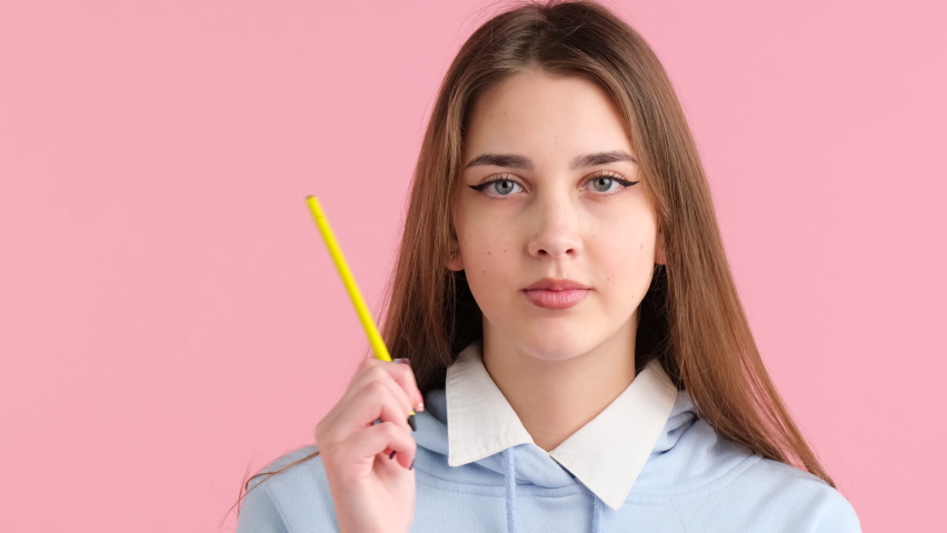 Thinking blonde teenage girl in school uniform with make-up looking aside holding a pen in her hand touching the head. Royalty-Free Stock Footage #1088812527
