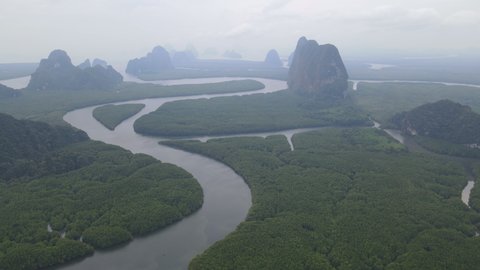 Top and aerial view fly over area of NAI HGOP pier of Ao Phang - Nga in Thailand to mountain and show line of water with mangroves along the sides and cloudy sky in evening look like raining.