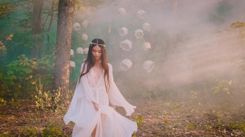Young beautiful woman elf, silver diadem crown on head. Long brunette hair. Princess girl in white silk medieval fantasy dress, nightgown, peignoir. Fashion model posing. foggy fairy autumn forest. 4k