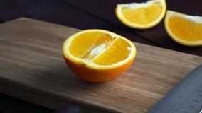 Man slicing raw orange with kitchen knife on wooden cutting board. Home cooking concept. Close-up