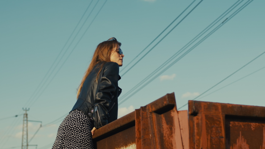 A young, beautiful rebel girl climbed onto an old rusty freight wagon