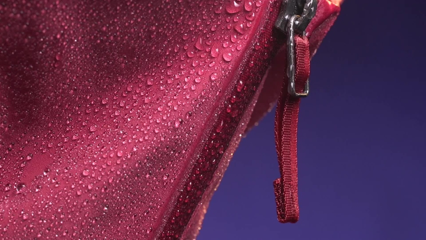 Close-up collar with zipper of the Gore-Tex membrane waterproof jacket under drops of a rain. Slow motion studio macro shooting. Royalty-Free Stock Footage #1088814019