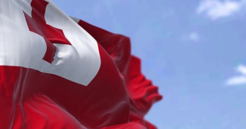 Detail of the national flag of Tonga waving in the wind on a clear day. Tonga is a Polynesian country and also an archipelago. Selective focus.  Seamless looping in slow motion