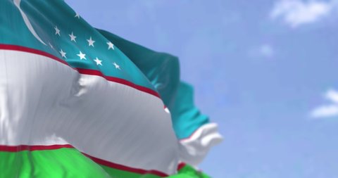 Detail of the national flag of Uzbekistan waving in the wind on a clear day. Uzbekistan is a landlocked country in Central Asia. Selective focus. Seamless looping in slow motion