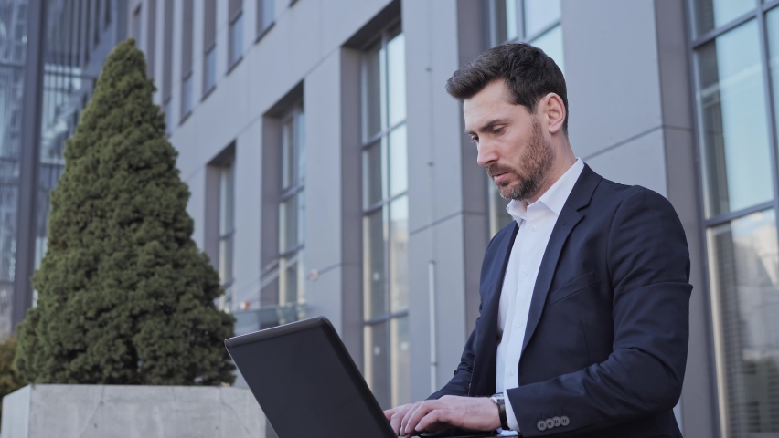 Overworked businessman looking at his watch no time is late, checking time near office place using laptop working typing message business man or lawyer in suit looking at expensive watch outdoors. Royalty-Free Stock Footage #1088814395