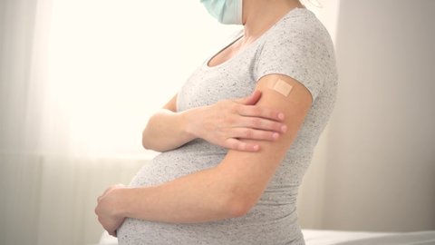 Vaccination of a pregnant woman. Close view of shoulder after vaccine injection with adhesive tape. Covid vaccination concept. Health and medicine during pregnancy.