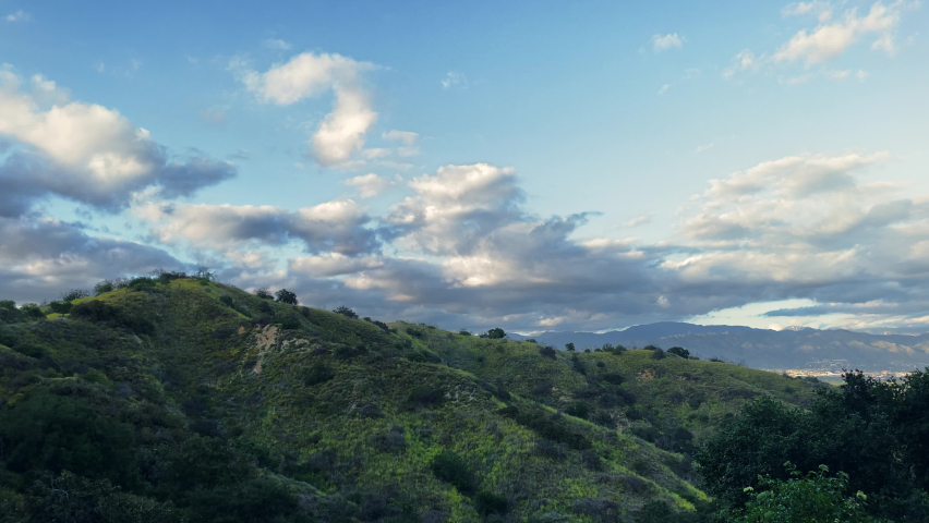 View from the Betty B Dearing Mountain Hiking Trail on the side of a mountain as white clouds fill the sky in Los Angeles, California