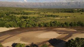Dry river with green banks and mountains in background, Cordoba, Argentina. Aerial panoramic view