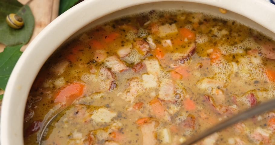 Woman hands putting pea soup in a white bowl, close up view from above. Tasty and delicious homemade dish.