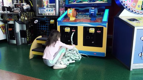 The little girl won at the slot machines. Game center in the mall. The device gives out the won prizes and tickets. Perm, Russia, March 31-2022